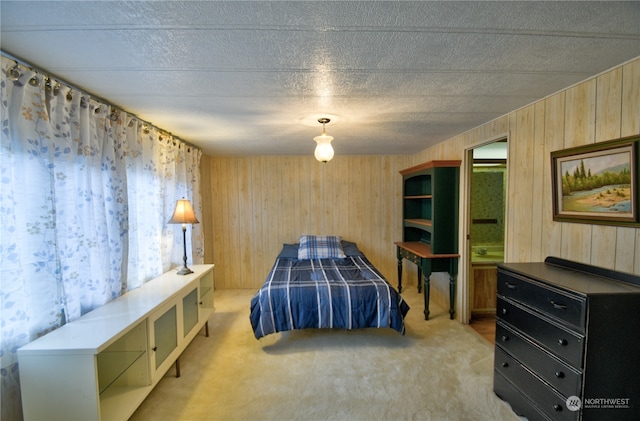 bedroom featuring light colored carpet and wooden walls