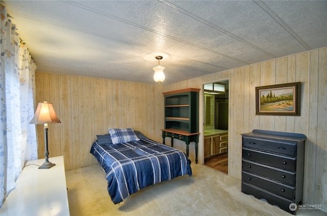 carpeted bedroom with ensuite bath and wood walls