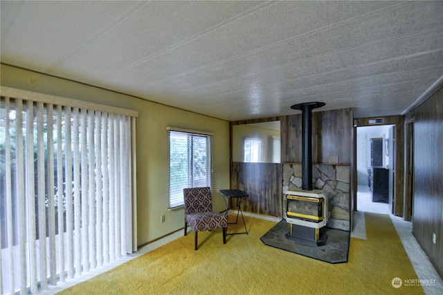 sitting room featuring light carpet, a textured ceiling, and a wood stove