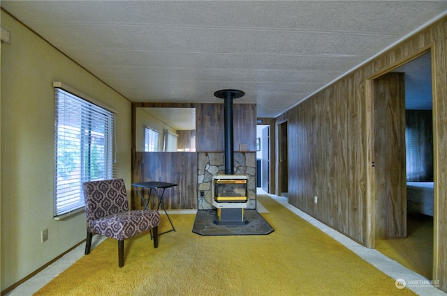 living area with carpet flooring, a wood stove, and wooden walls