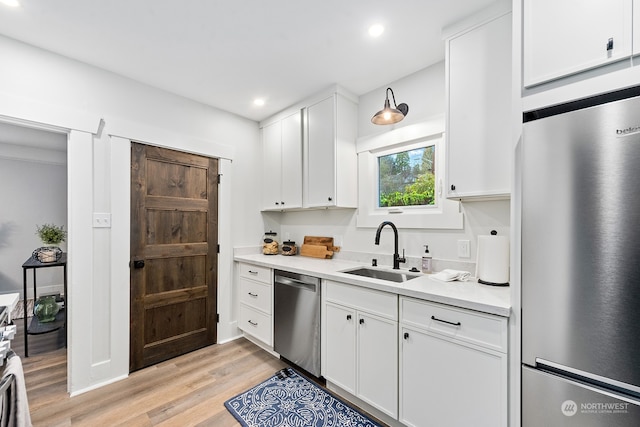 kitchen with sink, white cabinets, light hardwood / wood-style floors, and appliances with stainless steel finishes