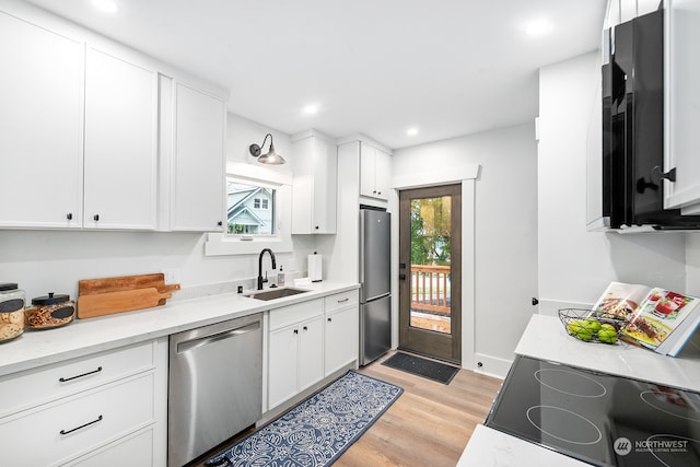 kitchen featuring white cabinets, light hardwood / wood-style floors, sink, and appliances with stainless steel finishes