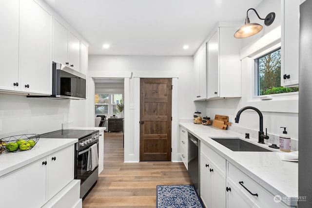 kitchen with stainless steel appliances, sink, light hardwood / wood-style flooring, white cabinetry, and plenty of natural light