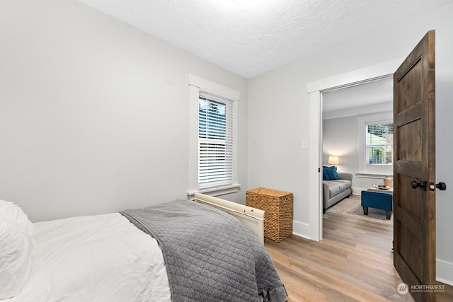 bedroom featuring light hardwood / wood-style floors and a textured ceiling