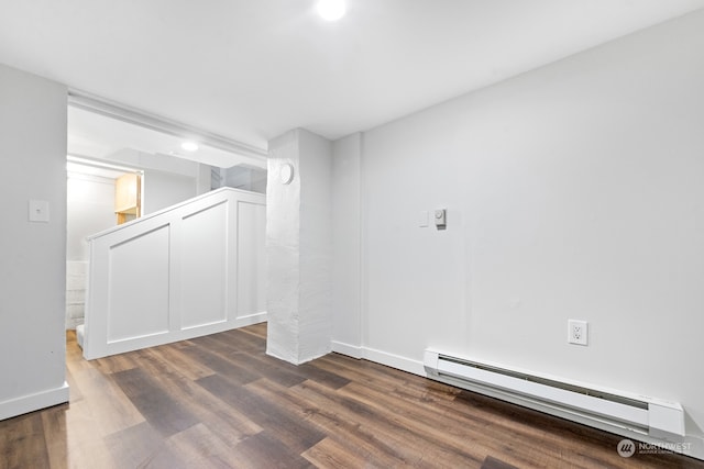 unfurnished room with dark hardwood / wood-style flooring and a baseboard heating unit