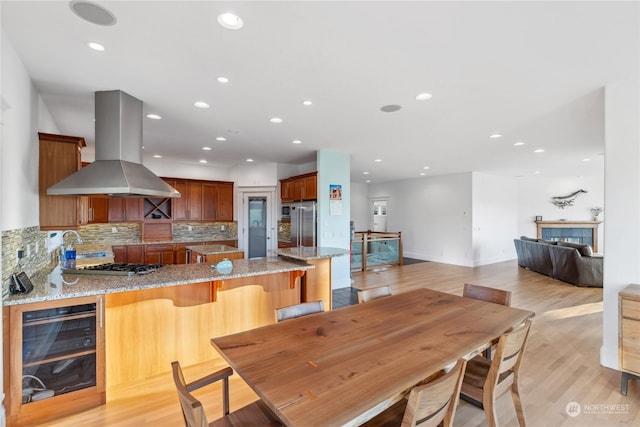 dining room featuring light wood-type flooring, a fireplace, and beverage cooler