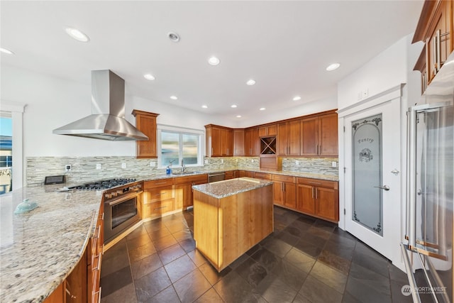 kitchen featuring decorative backsplash, a center island, light stone counters, and wall chimney exhaust hood