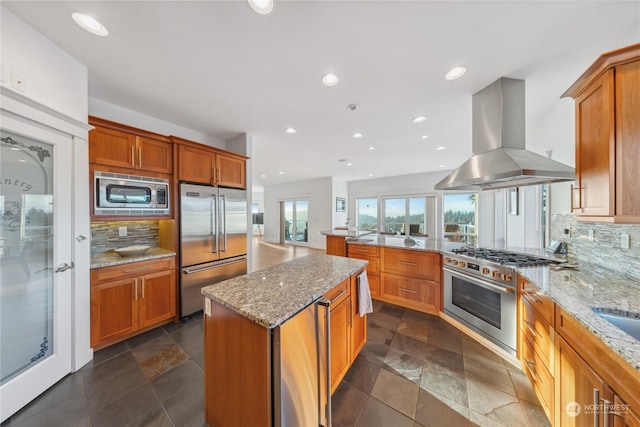 kitchen with a kitchen island, backsplash, extractor fan, and high quality appliances