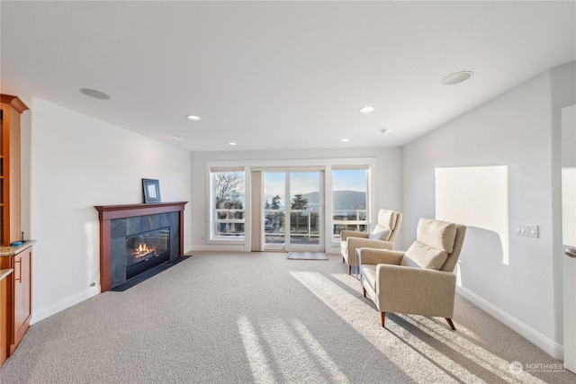 living area with a tile fireplace and light carpet