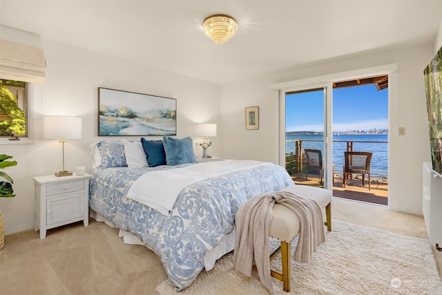 carpeted bedroom with access to exterior and a water view