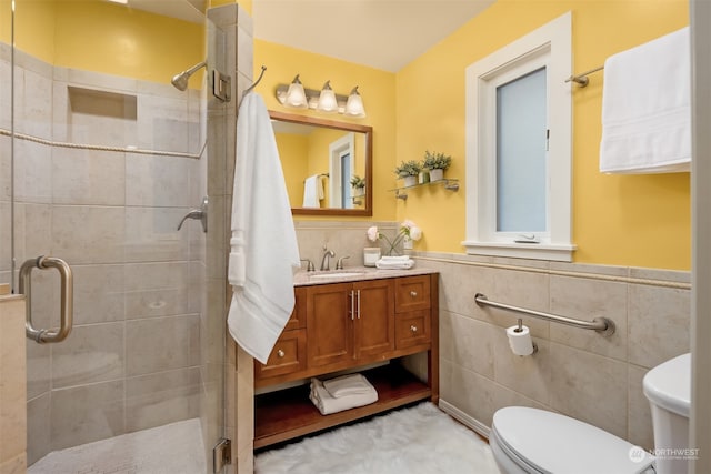 bathroom with a shower with door, vanity, tile walls, and toilet