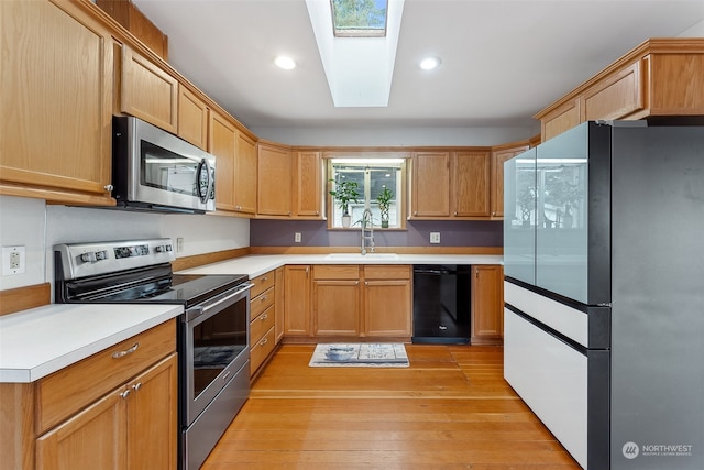 kitchen featuring a skylight, sink, stainless steel appliances, and light hardwood / wood-style floors