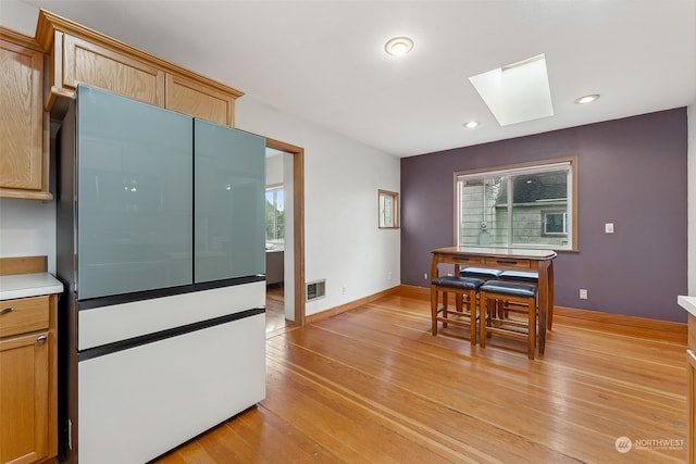 kitchen with a healthy amount of sunlight, a skylight, light brown cabinetry, and light hardwood / wood-style flooring