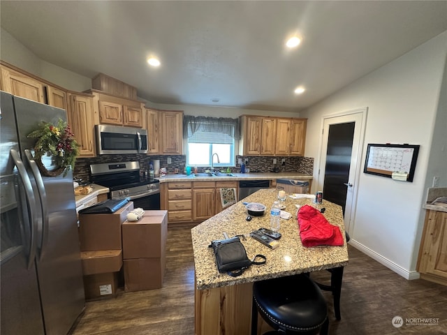 kitchen featuring light stone countertops, a center island, sink, stainless steel appliances, and dark hardwood / wood-style floors