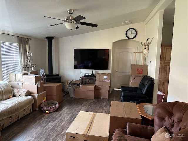 living room featuring dark hardwood / wood-style floors, ceiling fan, a wood stove, and vaulted ceiling