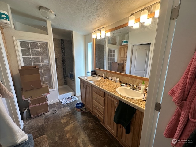 bathroom featuring vanity, a textured ceiling, and tiled shower