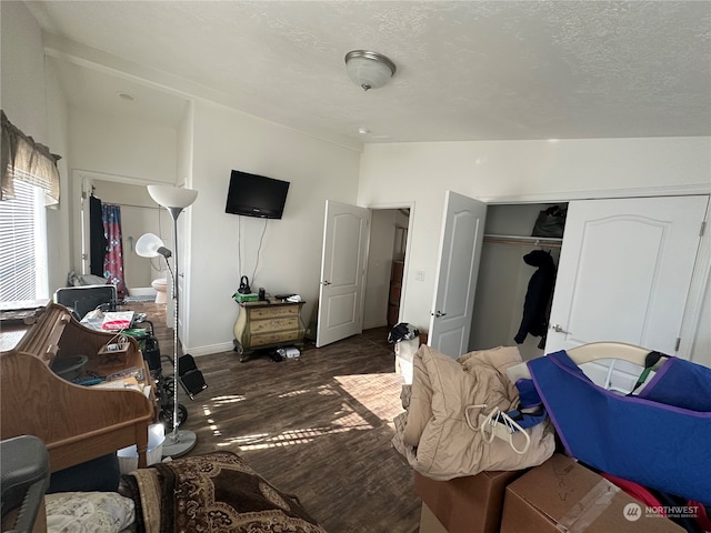 bedroom with dark hardwood / wood-style flooring, a textured ceiling, and a closet