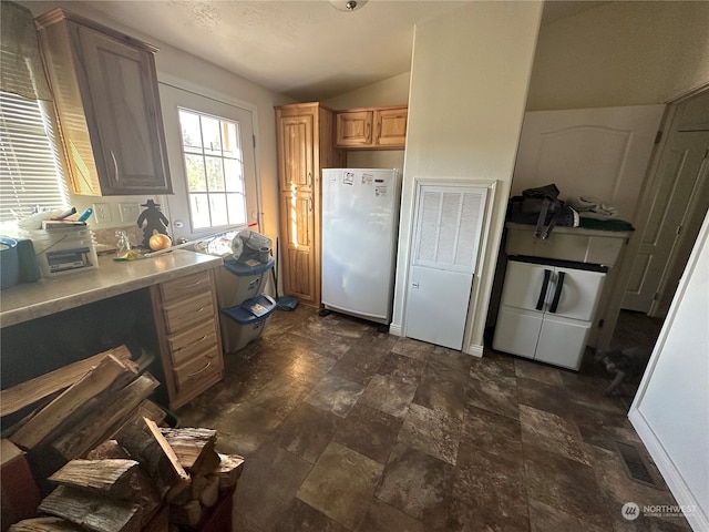 kitchen featuring white fridge, lofted ceiling, and washing machine and clothes dryer