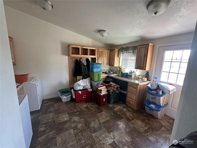 kitchen featuring lofted ceiling, a textured ceiling, and washing machine and clothes dryer