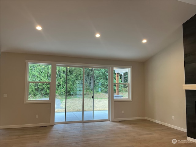 unfurnished living room featuring vaulted ceiling and light hardwood / wood-style flooring