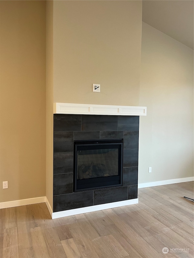 interior details featuring wood-type flooring and a tile fireplace