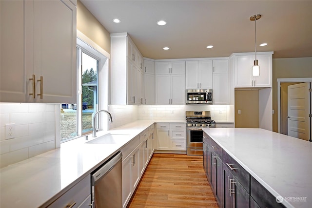 kitchen with white cabinets, appliances with stainless steel finishes, pendant lighting, and sink