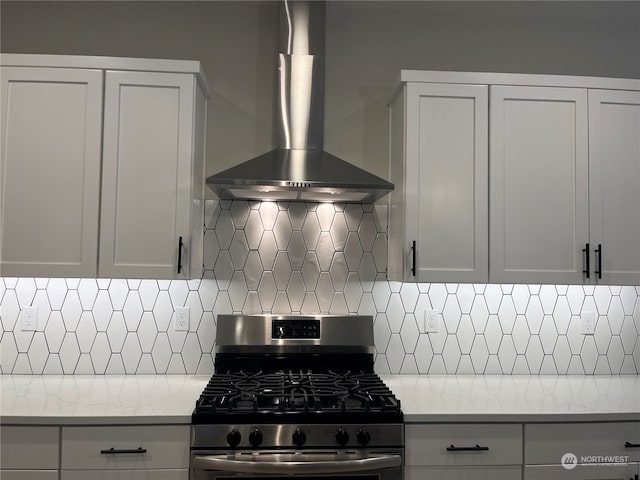 kitchen with gas stove, decorative backsplash, white cabinetry, and wall chimney range hood