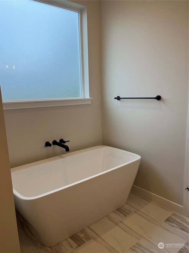 bathroom featuring a bath and a wealth of natural light