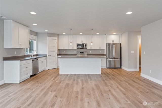 kitchen featuring pendant lighting, white cabinetry, sink, a center island, and stainless steel appliances