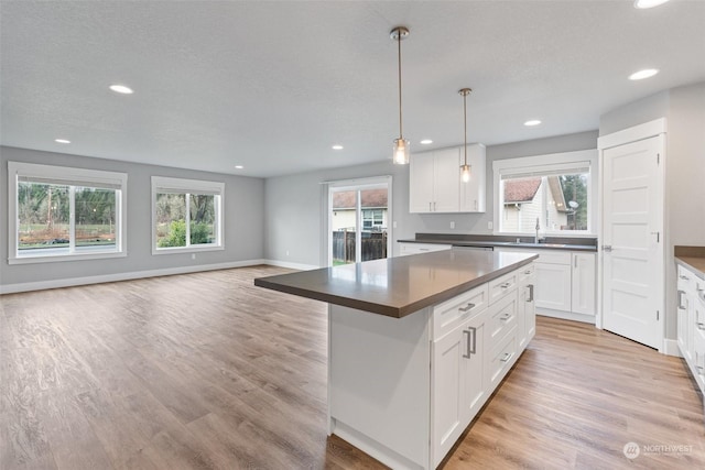 kitchen featuring hanging light fixtures, a kitchen island, white cabinets, and light wood-type flooring