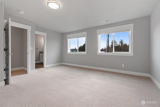 unfurnished bedroom with ensuite bath and light colored carpet