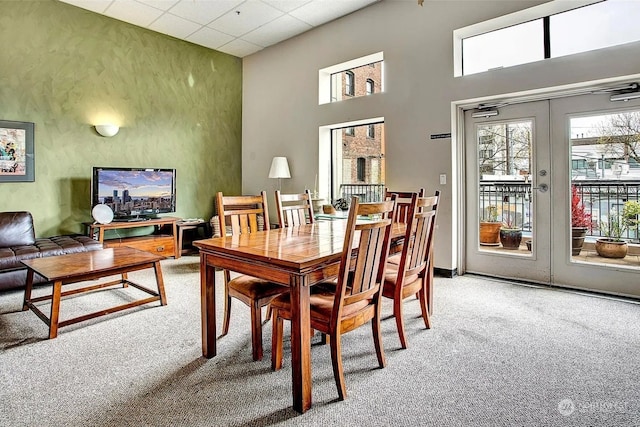 carpeted dining space featuring a drop ceiling and french doors