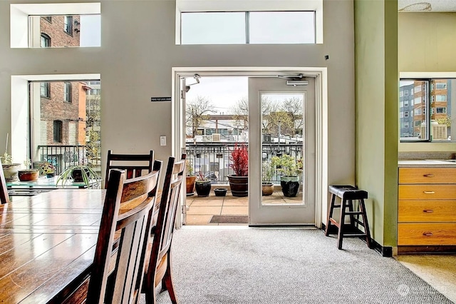 doorway to outside with a towering ceiling and light carpet