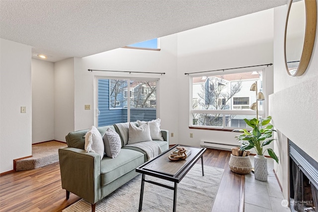 living room with wood-type flooring, a textured ceiling, a wealth of natural light, and a tiled fireplace