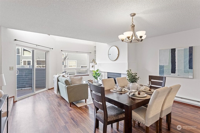 dining room featuring a chandelier, dark hardwood / wood-style flooring, a baseboard radiator, and a textured ceiling