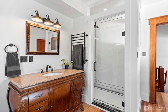 bathroom featuring wood finished floors, vanity, and a stall shower