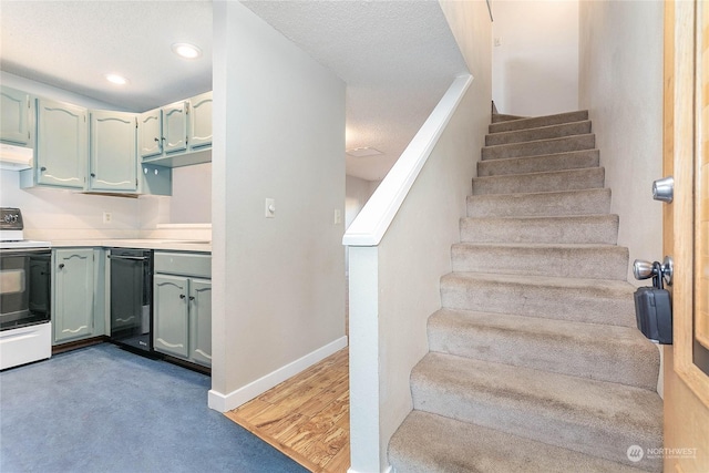 staircase with a textured ceiling and hardwood / wood-style flooring