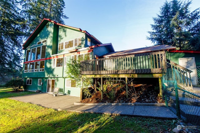 back of property with a sunroom, a patio, and a wooden deck