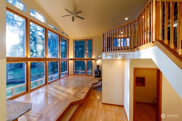 interior space with a wood stove, ceiling fan, and vaulted ceiling