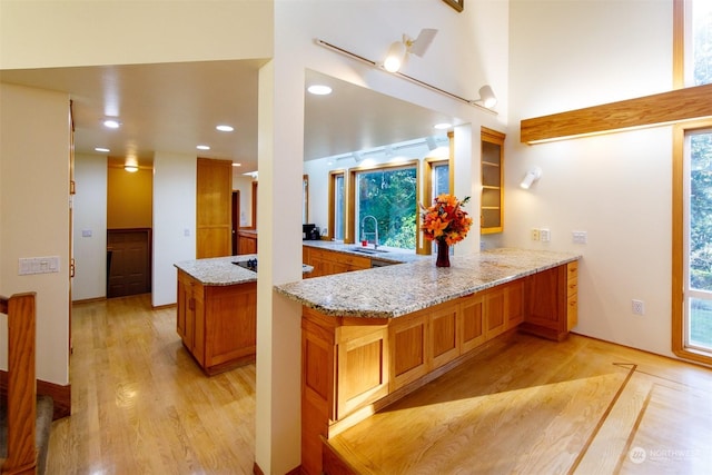 kitchen featuring kitchen peninsula, light hardwood / wood-style floors, light stone countertops, and sink