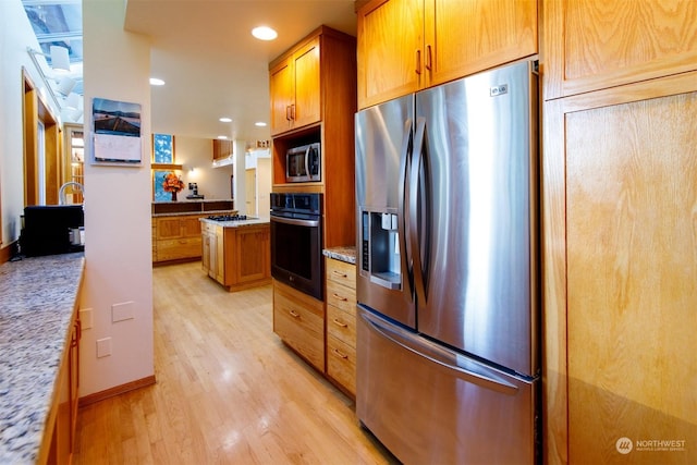 kitchen featuring light stone countertops, stainless steel appliances, and light hardwood / wood-style flooring