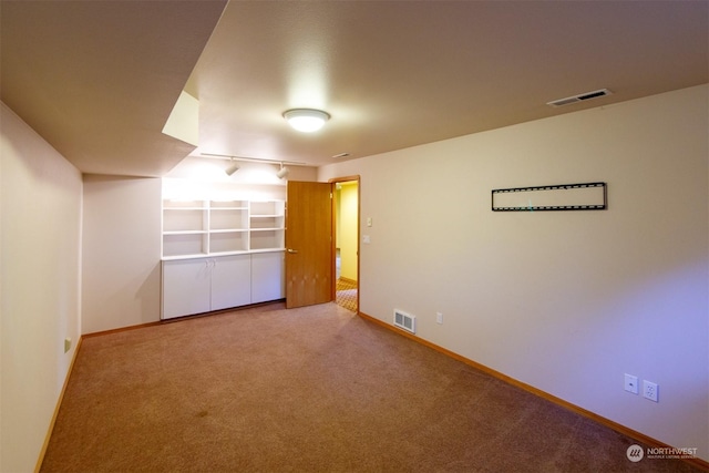 carpeted empty room featuring rail lighting