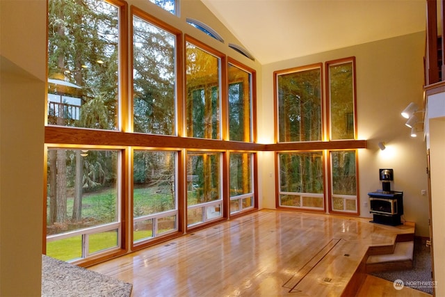 unfurnished sunroom with lofted ceiling and a wood stove