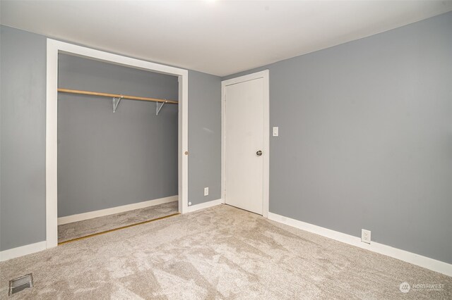 unfurnished bedroom with a closet and light colored carpet