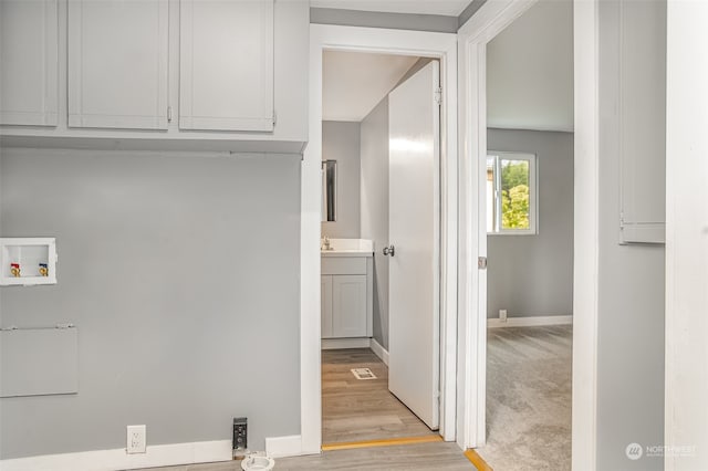 washroom featuring cabinets, sink, hookup for a washing machine, and light hardwood / wood-style flooring