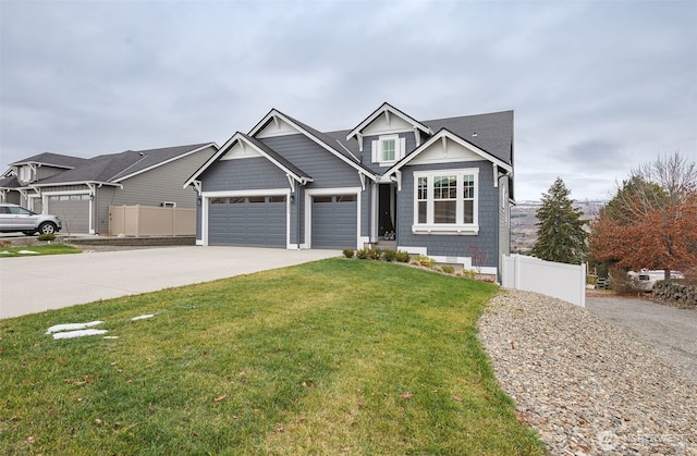 craftsman house with driveway, a garage, fence, and a front lawn