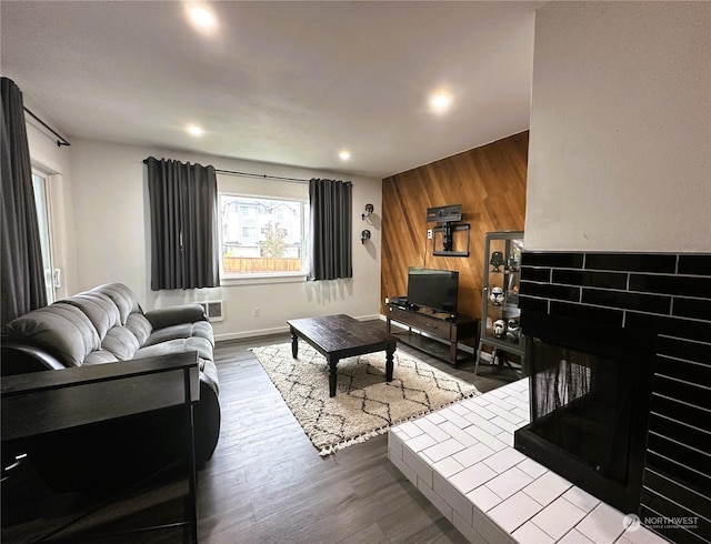 living room with a multi sided fireplace, light hardwood / wood-style floors, and wood walls