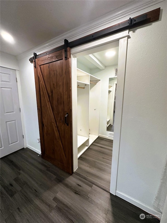 corridor with a barn door and dark hardwood / wood-style flooring