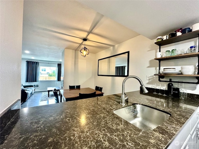 kitchen with hanging light fixtures, sink, and dark stone counters