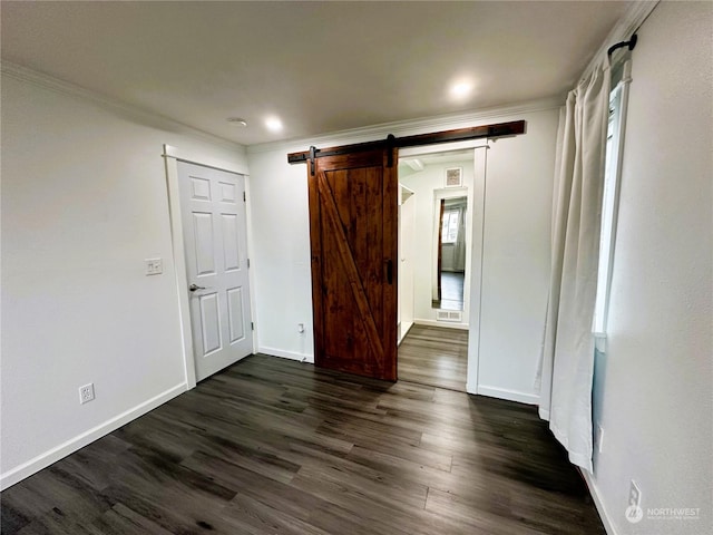 spare room with dark hardwood / wood-style floors, a barn door, and ornamental molding